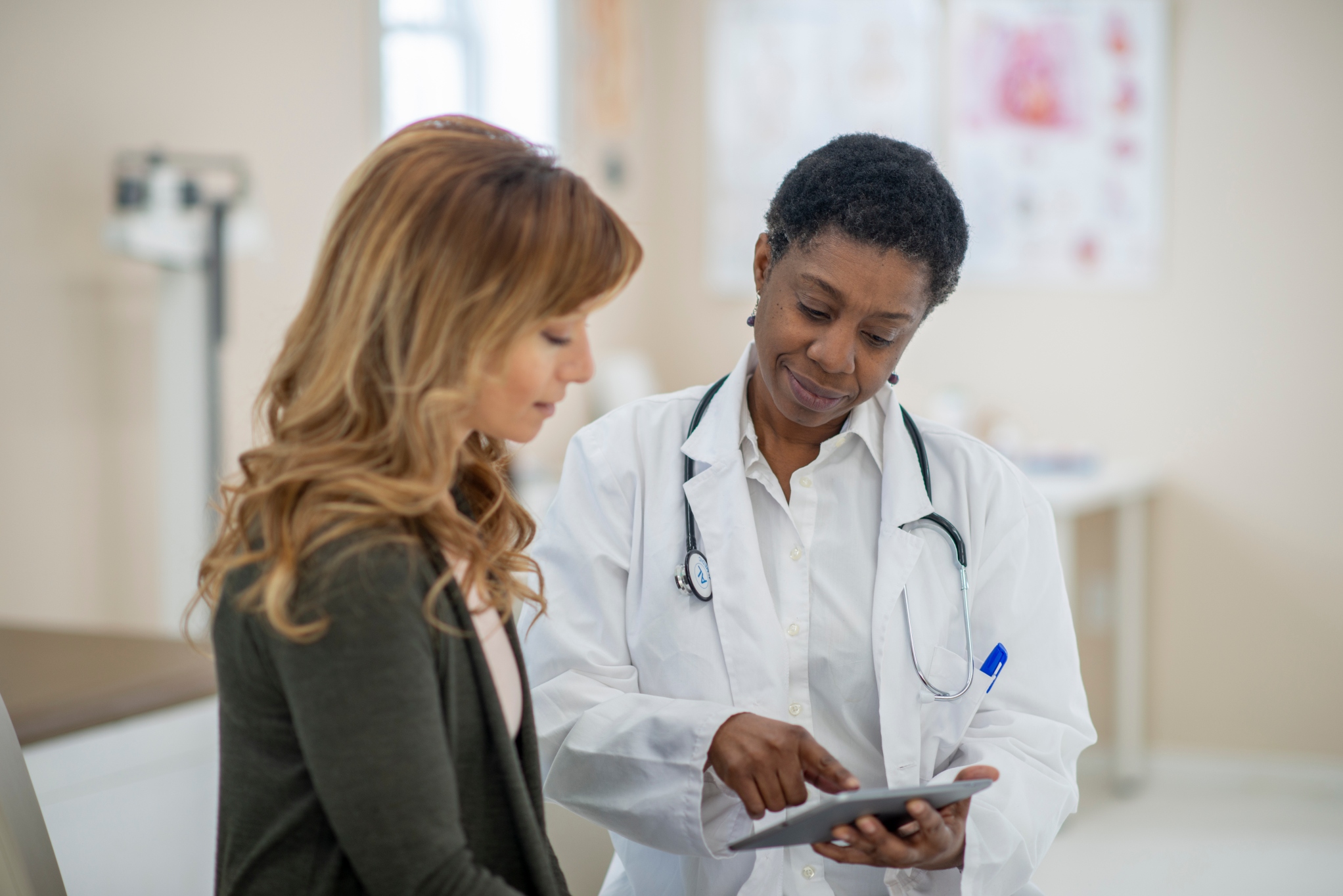 Woman in an exam room looking at their results with a doctor.