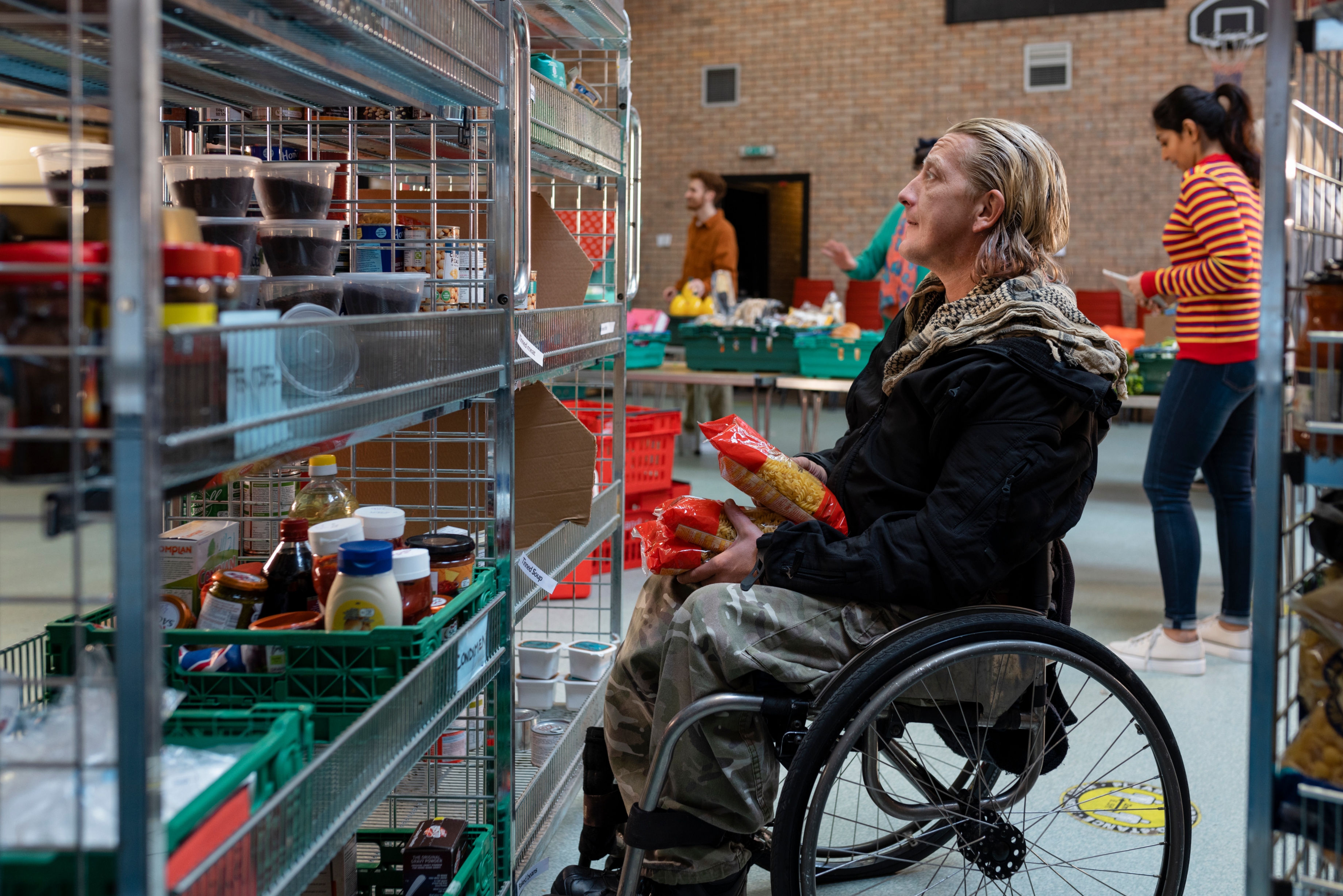 A volunteer in a wheelchair arranging food donations at a foodbank. 