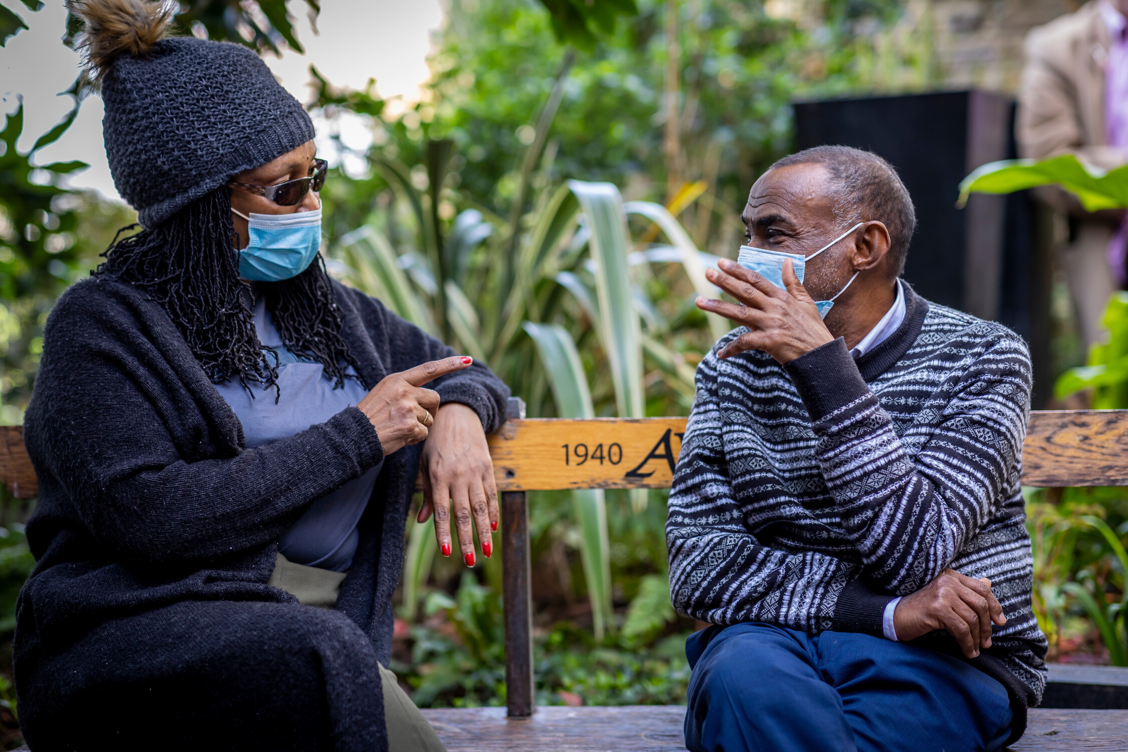 Two people sat on a bench outside having a discussion