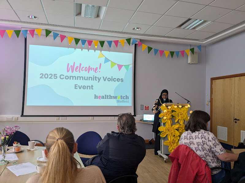 Safiya Saeed, the Right Honorable Lord Mayor of Sheffield, is stood at a podium giving a speech in front of a projection of a PowerPoint slide with text welcoming guests to the event