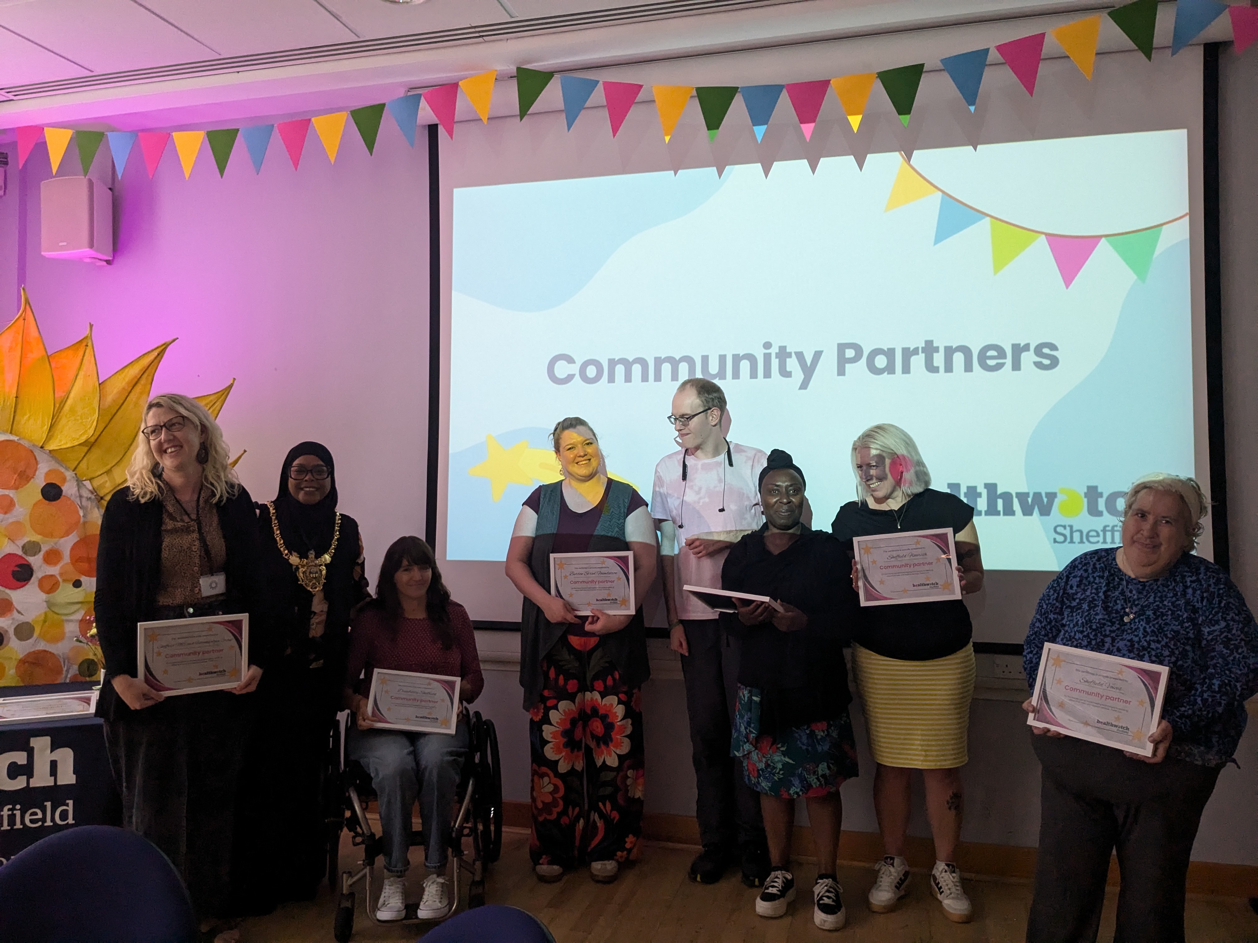 Community partners stood in front of a projected PowerPoint slide with text that reads 'Community Partners'