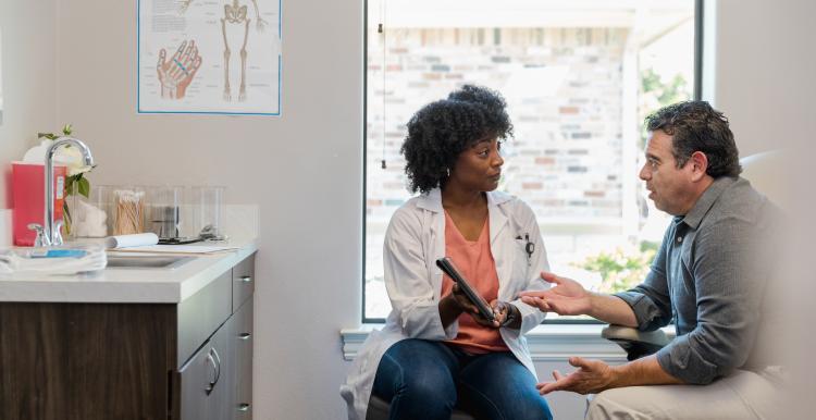 Female health professional points out information on a tablet to a male patient