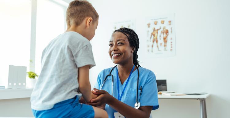 Young child sitting on a hospital bed speaking to a female doctor