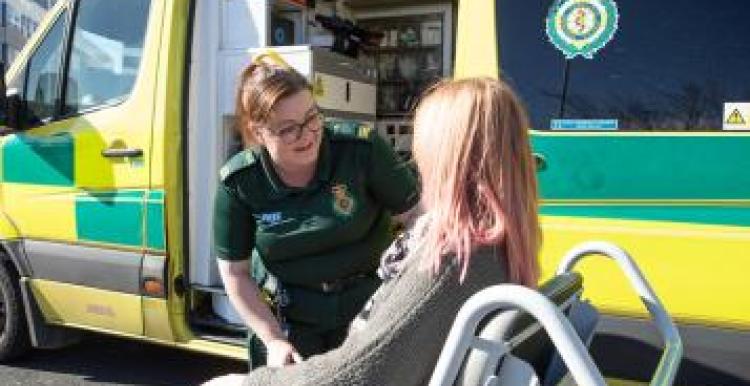 A staff member is supporting the patient to access patient transport.