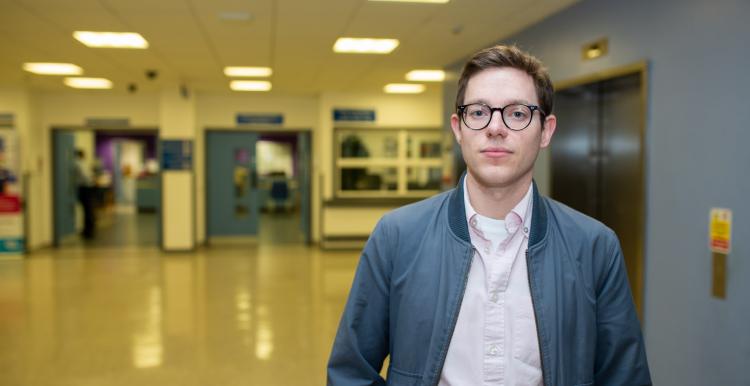 Young man standing face on to camera in a hospital hallway