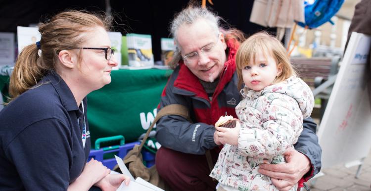 Healthwatch volunteer speaking to a grandparent and child at an event