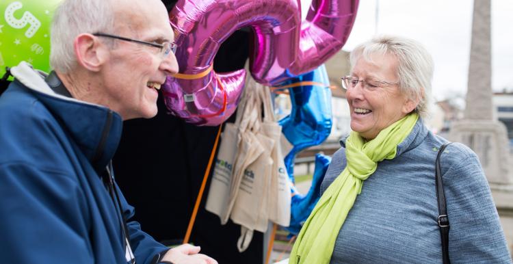 Elderly man and woman talking together at a Healthwatch event