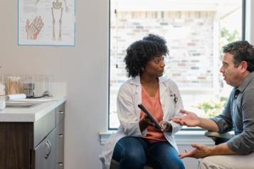 Female health professional points out information on a tablet to a male patient