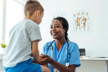 Young child sitting on a hospital bed speaking to a female doctor