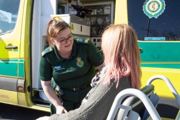 Wheelchair user speaking with a patient transport staff member. 