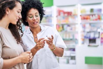 Hospital pharmacist reading information to a patient on a medication box.