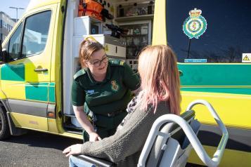 A staff member is supporting the patient to access patient transport.