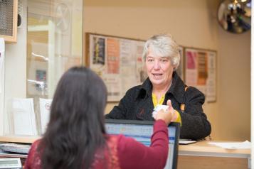 Female patient speaking with a receptionist 