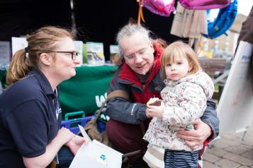 Healthwatch volunteer speaking to a grandparent and child at an event