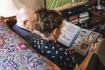 Carer and elderly man look at photo album together