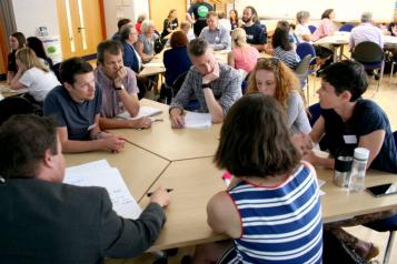Attendees talking around a table at a Health & Wellbeing Forum