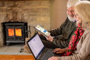 An older couple using a laptop and tablet