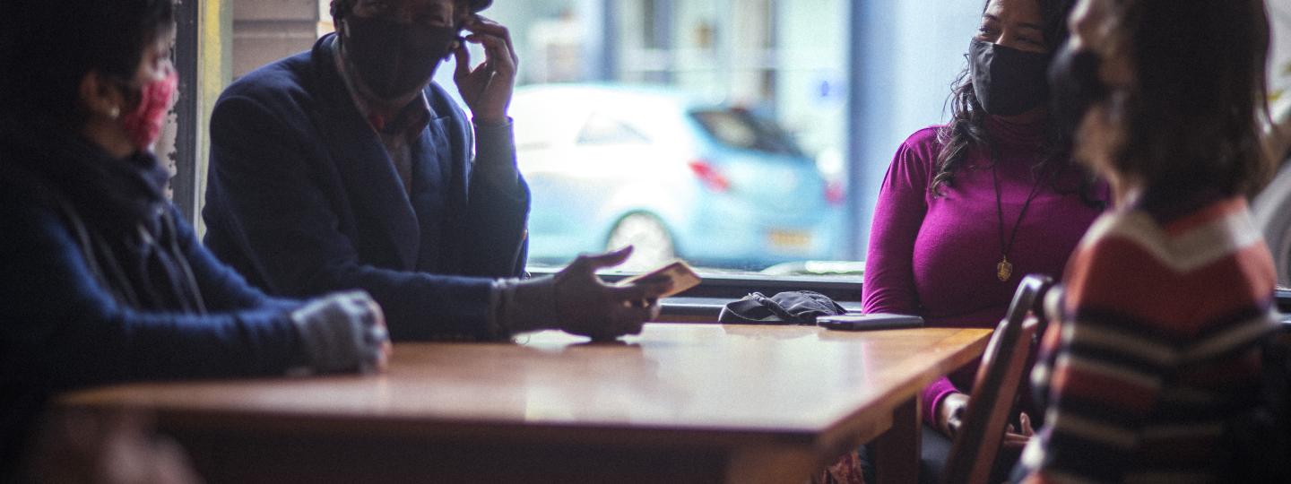 Group sitting in a cafe wearing face coverings
