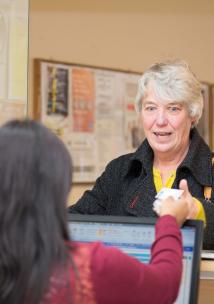 A woman talking to another woman behind a reception desk